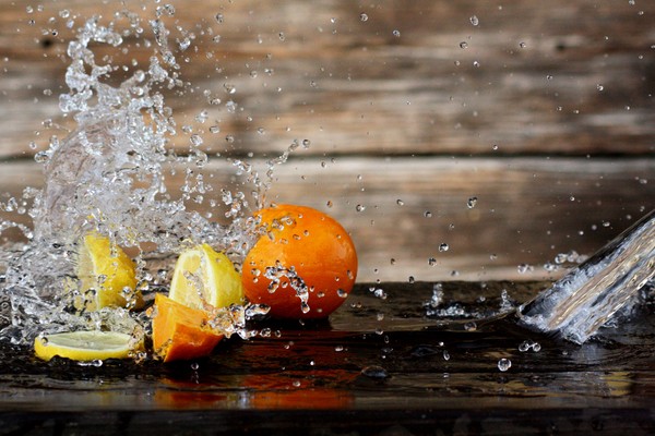 Um Zitronen und Orangen spritzt Wasser.
