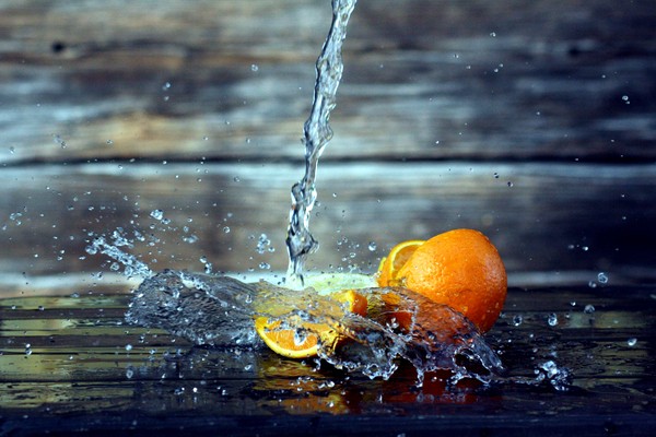 Ein Wasserstrahl spritzt auf eine aufgeschnittene Orange