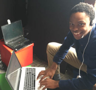 Junge mit Headset sitzt vor MacBook