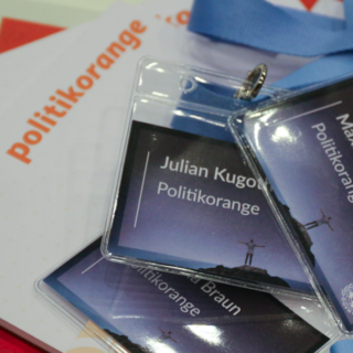 politikorange-notizblag und Namensschilder der YouthCon 2016 für die Redakteure liegen auf einem Haufen. Foto: Charles Lothar