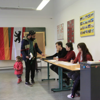 Mann gibt Stimmzettel im Wahllokal ab.