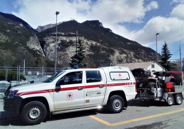 Eine Ambulanz des roten Kreuzes steht vor hügeliger Landschaft.