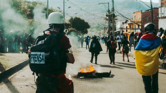 Ein Autoteil steht in Flammen bei Protesten in Kolumbien. Foto: Vision ekstase / Bella Christmann