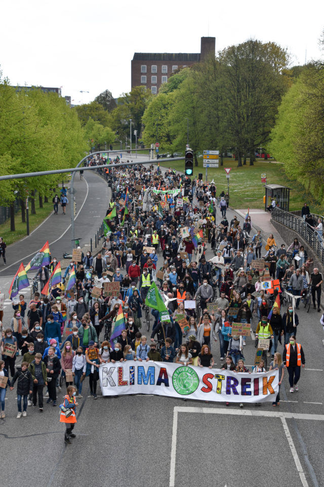 Viele Menschen stehen auf einer Straße, vor sich ein Banner, auf dem steht: Klimastreik.