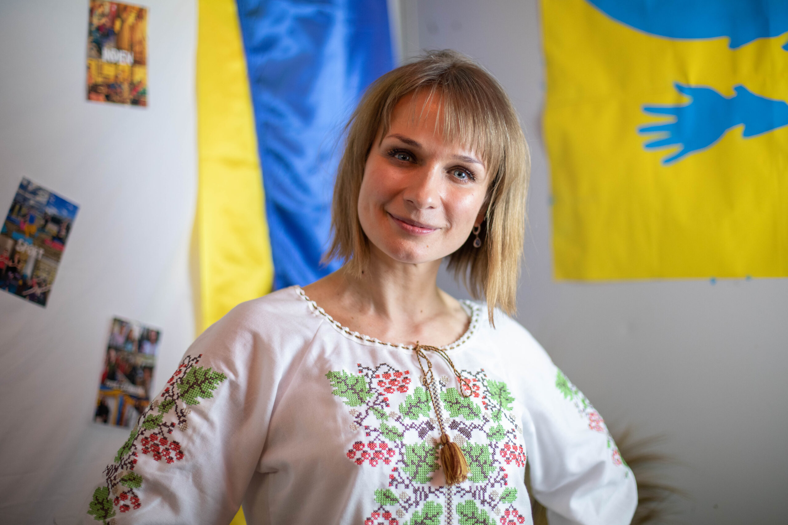 Es ist eine lächelnde Frau zu erkennen und im Hintergrund die ukrainischen Farben.