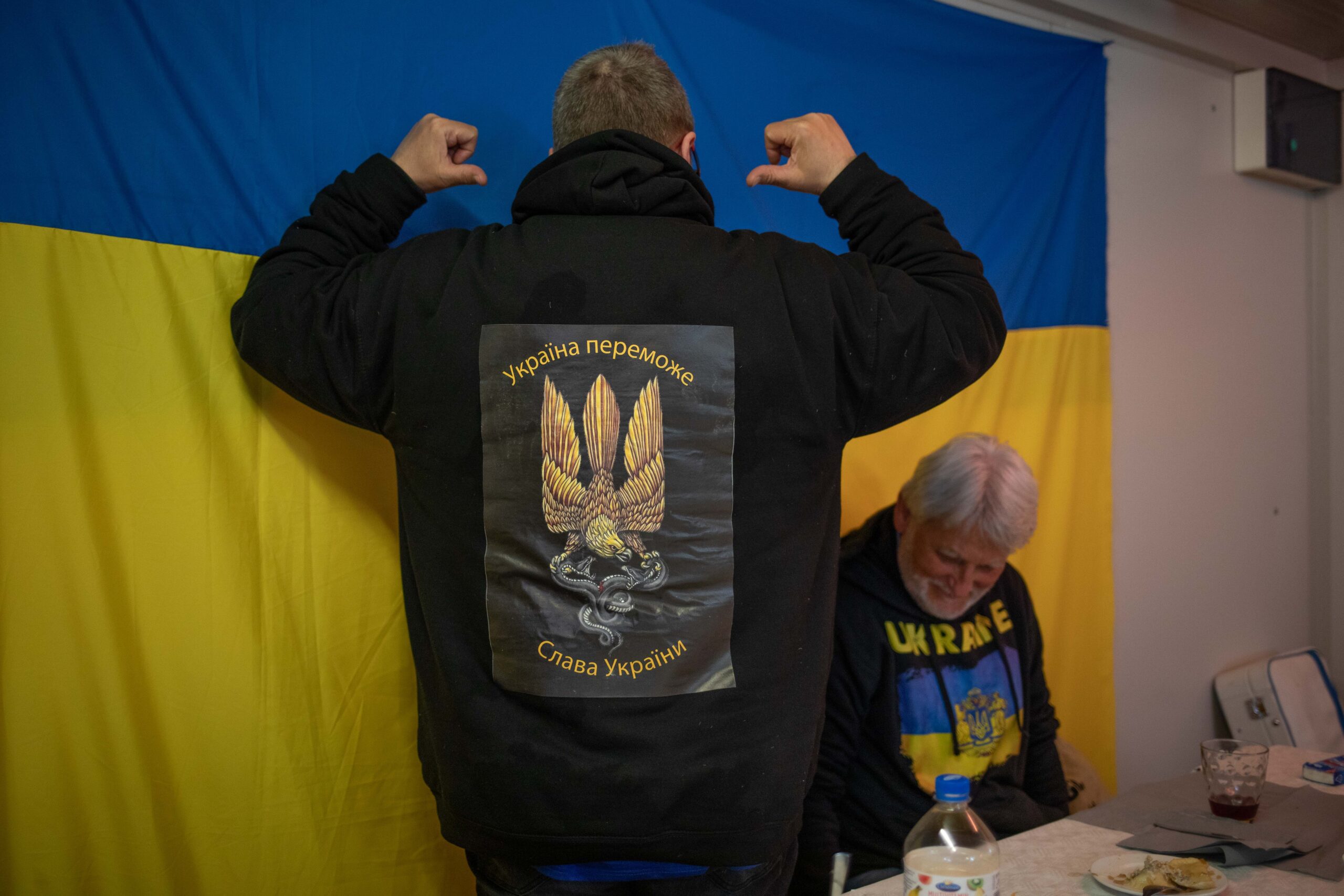 Es ist der Rücken eines Mannes zu erkennen auf dessen Rücken das ukrainische Zeichen für Sieg zu sehen ist.