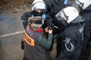 Ein*e Polizist*in entwendet einem*r Journalist*in ihr Telefon beim Versuch Jörg Reichel vom Journalist*innenverband zu erreichen.