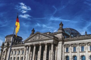 Das Reichstagsgebäude steht im Mittelpunkt. Links ist eine deutsche Flagge erkennbar.