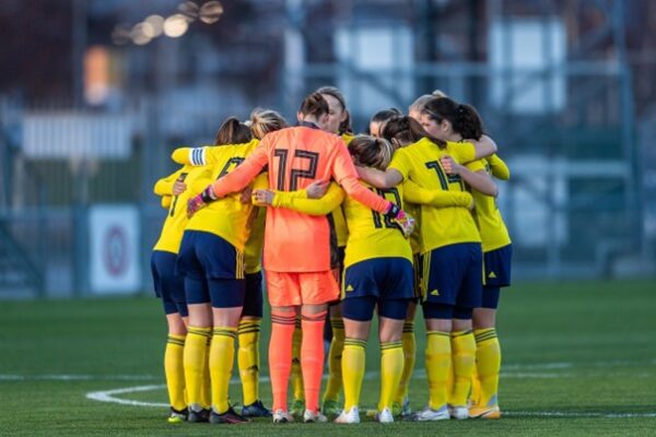 Eine Frauen-Fußballmannschaft bespricht sich auf dem Platz. 