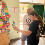Redaktionsteilnehmer Klaas hält einen Selfiestick mit einem Handy in der Hand. Hinter ihm steht zur Unterstützung Christian von fjp>media. Beide schauen auf den Bildschirm des Handys.